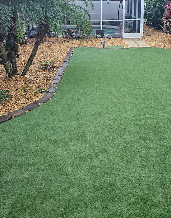 A lush, evergreen residential backyard featuring premium artificial turf installation, providing a mud-free and low-maintenance outdoor space.
