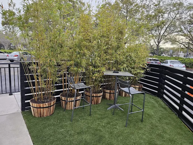 Artificial turf and bamboo plants in half-barrel planters in a commercial seating area