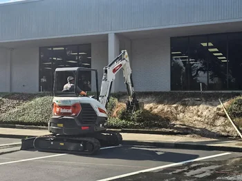Landscaper using a Bobcat mini-excavator to clear brush at a commercial property in Sanford