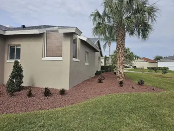 Beautiful landscape design with red rock beds and a clean lawn in Winter Park