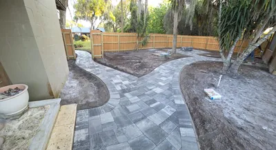 Curved paver walkway leading to a backyard firepit during a landscaping project