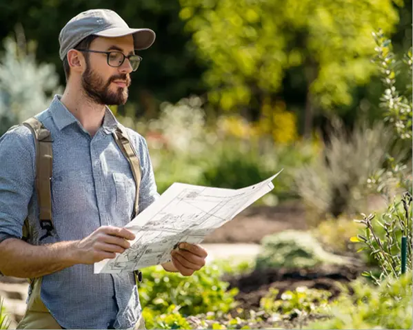 Custom Landscape Designer inspecting site & plan