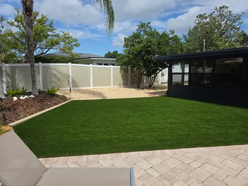 Full view of a Sanford backyard with artificial turf, walkway, stone, and plants