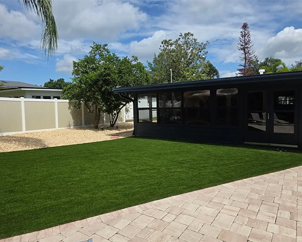 Lush artificial grass backyard with clean stone borders, showcasing a beautiful and modern low-maintenance outdoor landscape design.